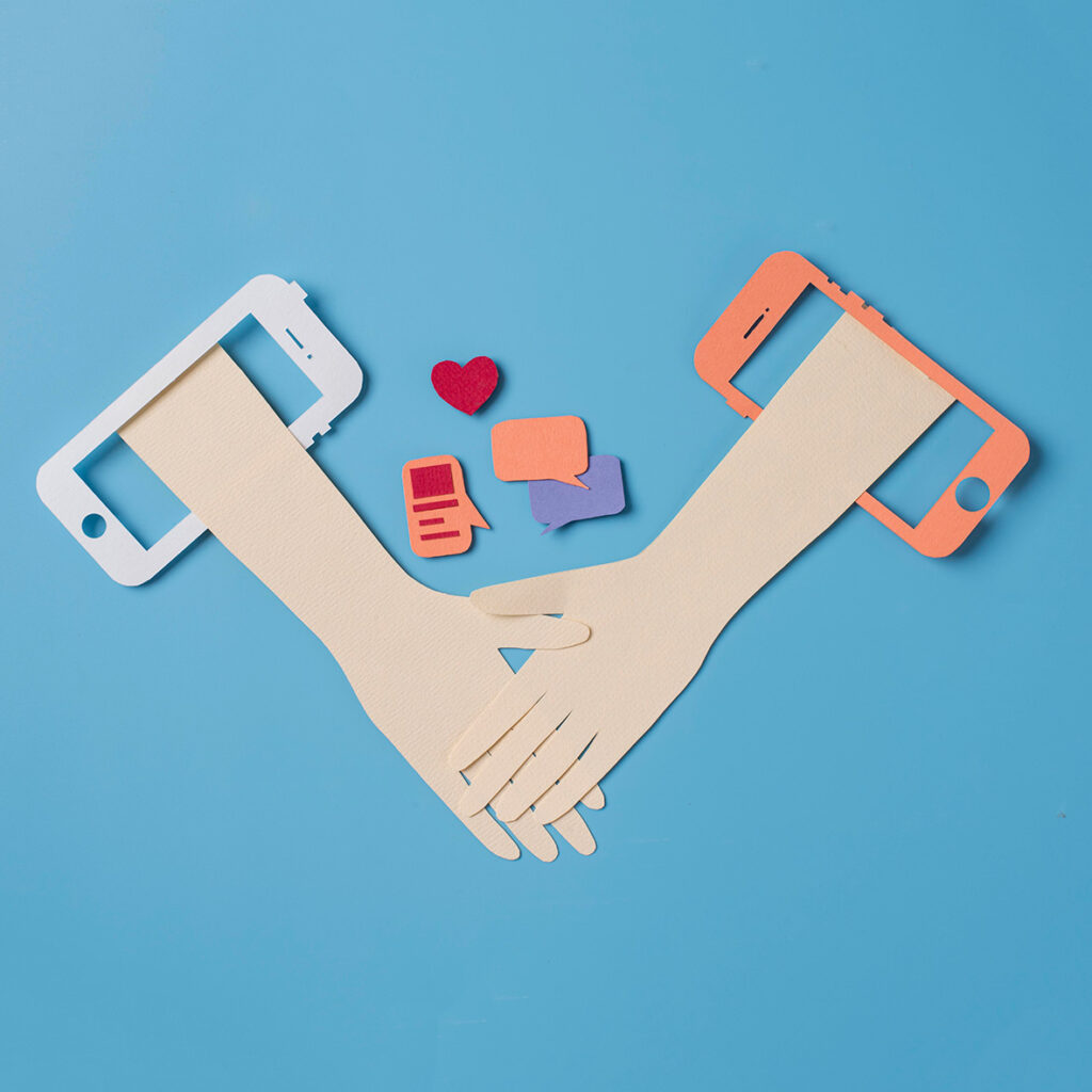 Manos de papel unidas, con teléfonos de papel a los lados y símbolos de conversación en el fondo, sobre un fondo azul. Otras webs de ayuda